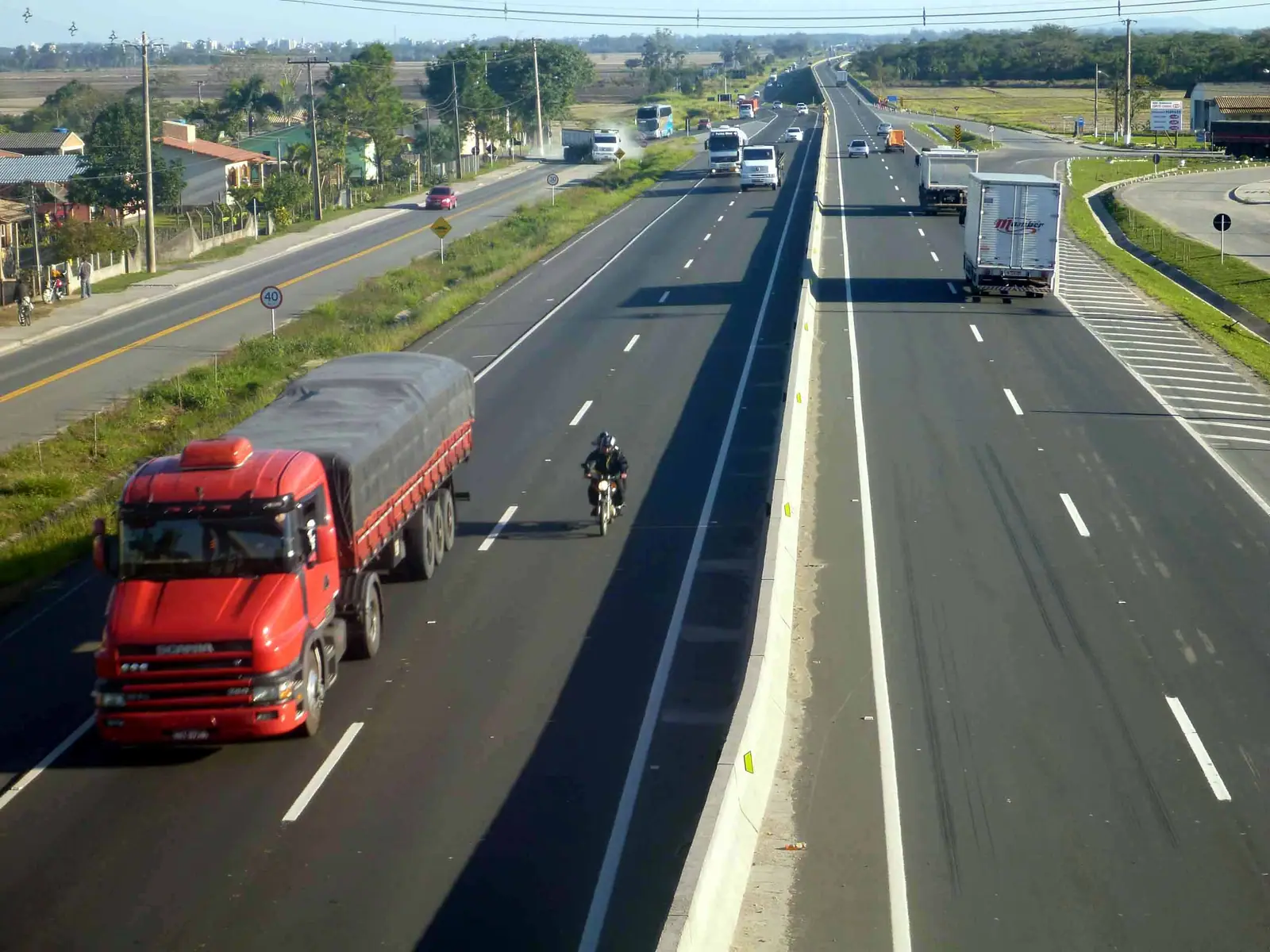 Pista duplicada da BR-101 em trecho de litoral com morros ao fundo